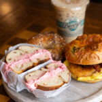 Bagel sandwich with pink cream cheese and iced coffee with logo
