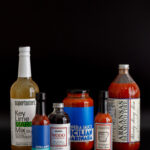 Five bottles and jars of sauces and mixes, including Key Lime Mix, Mediterranean Hot Sauce, and